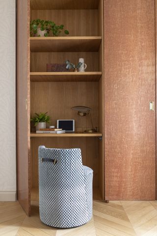 home office closet style with shelving, upholstered stool/seat, herringbone flooring, door, lamp