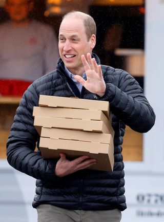 Prince William carrying boxes of pizza