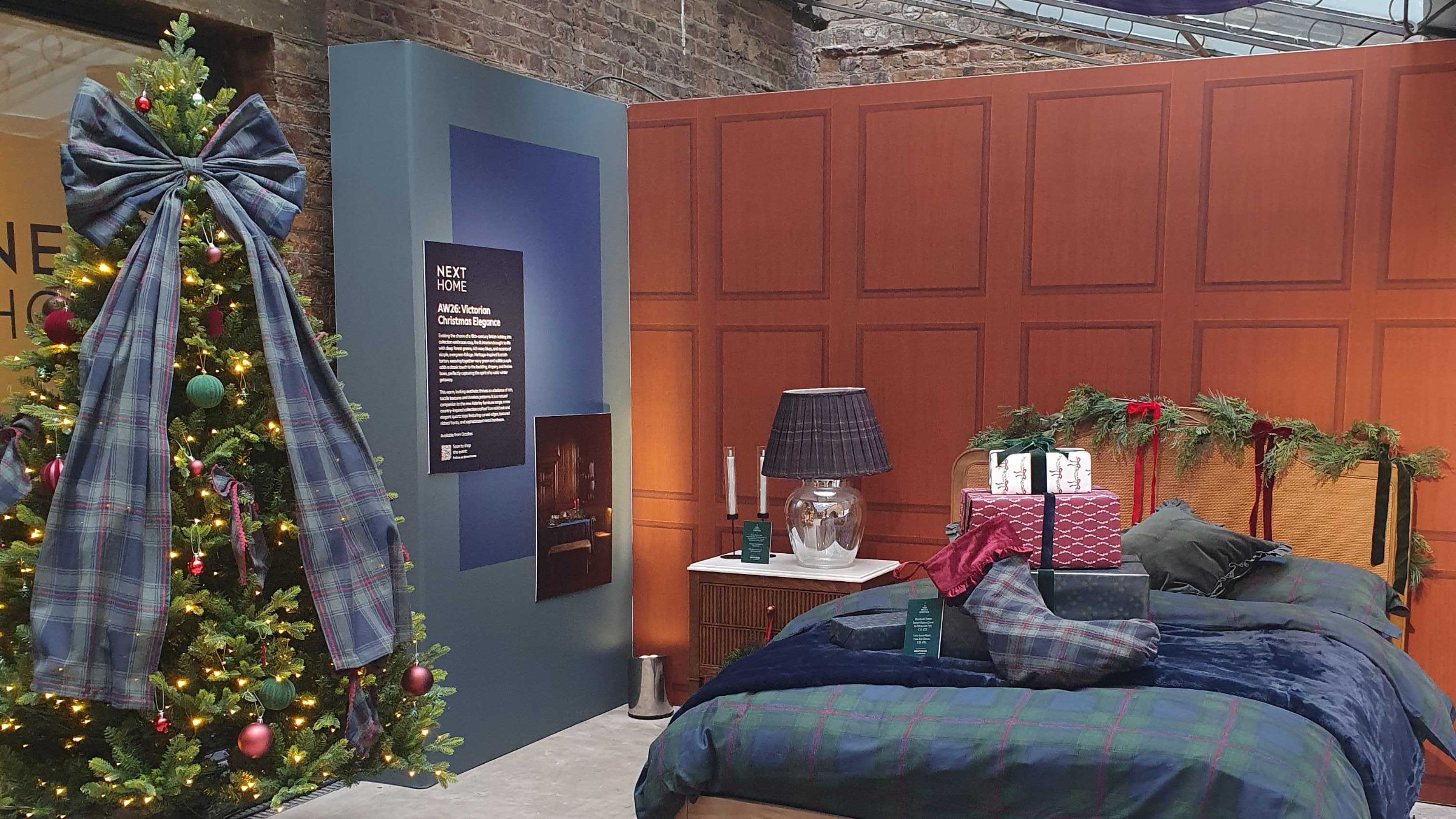 A Christmas bedroom set-up at the Next Christmas 2026 press preview with a Christmas tree decorated with the brand's extra large tartan bow tree topper