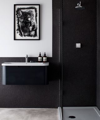 An example of modern bathroom ideas showing a black shower room with a white feature wall with art hanging up