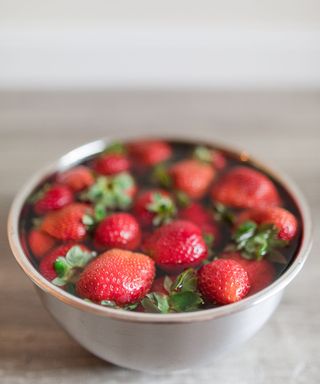 Strawberries in a metal bowl of water