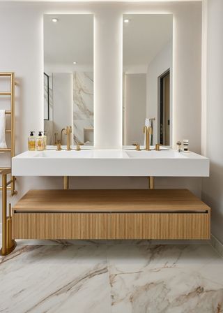 Two large mirrors with a sink and storage beneath it. There are also two golden taps placed onto the sink