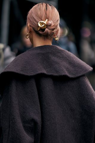 A person with a low bun and gold hair accessory at Paris fashion week