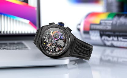 A black Zenith wristwatch with colourful dials and hands resting on the edge of a laptop