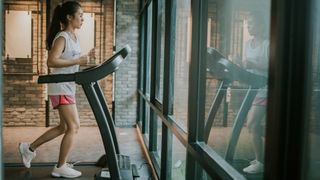 Woman running on treadmill at the gym, looking out of the window