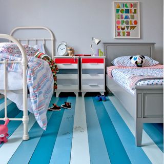 bedroom with twin beds, blue floorboards and drawers