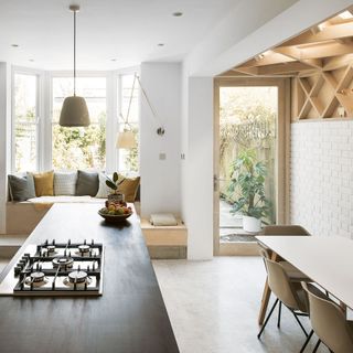 open plan kitchen diner with bay window seat and striking timber lattice work on wall and ceiling