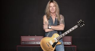 Doug Aldrich poses with his Goldtop Les Paul in front of his signature Blackstar Ruby amp.