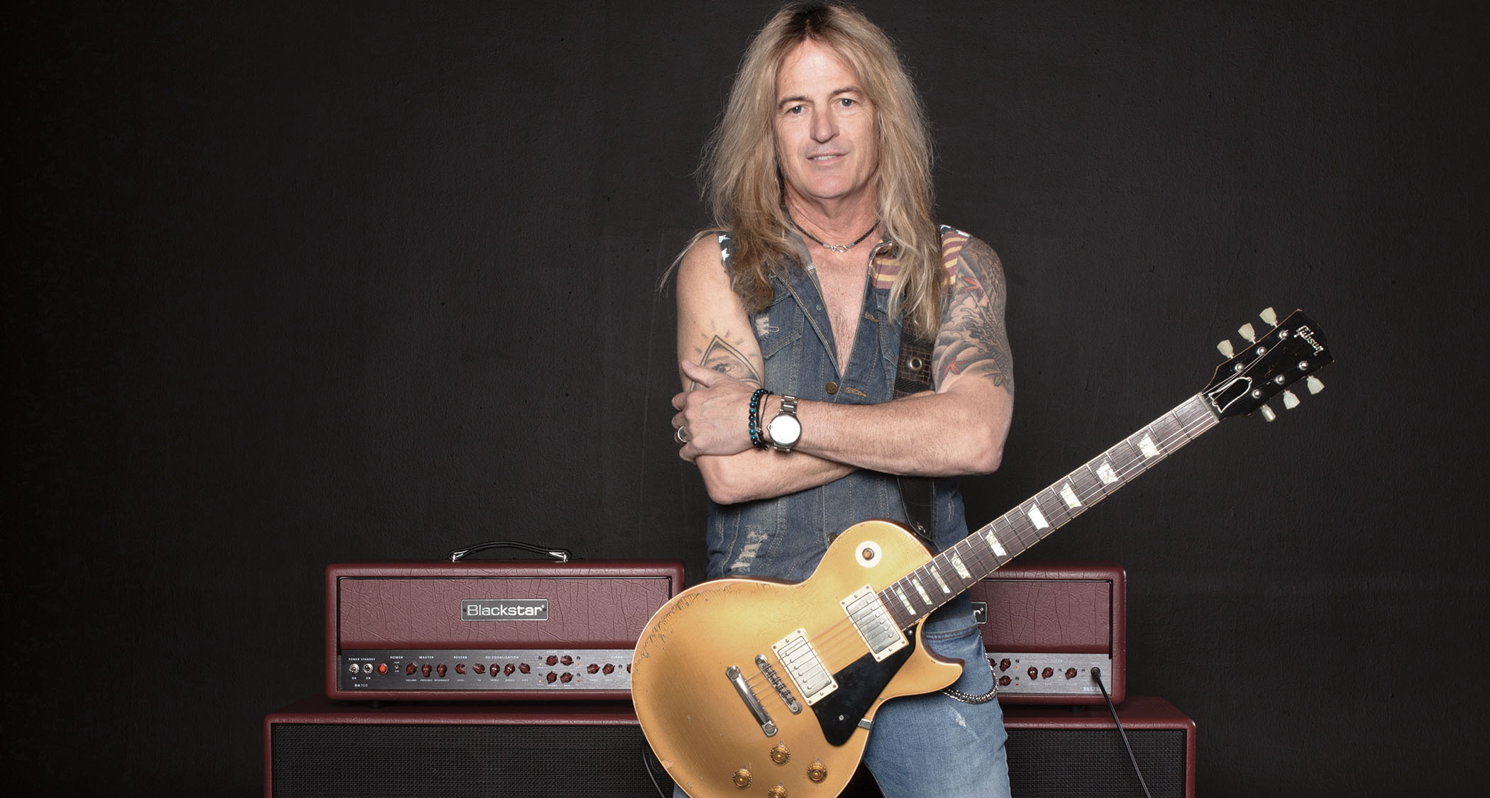 Doug Aldrich poses with his Goldtop Les Paul in front of his signature Blackstar Ruby amp.