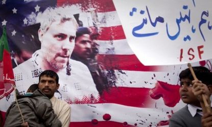 Pakistani protesters stand next to a banner bearing an image of US CIA contractor Raymond Davis who was brought up on murder charges after shooting Pakistani civilians in January.