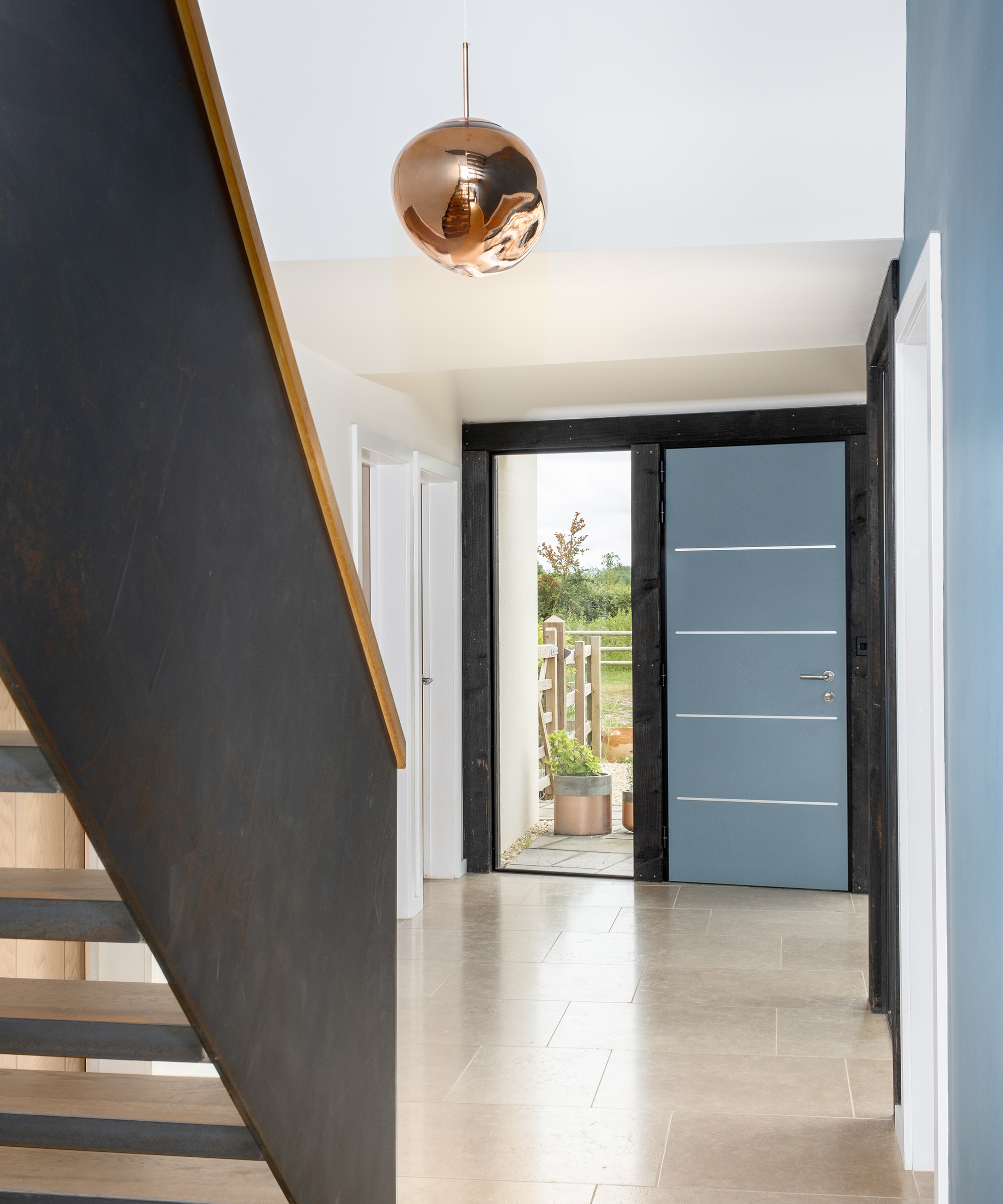 A front hallway with a blue front door and black staircase