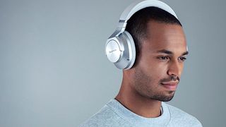 Best headphones: Technics EAH-A800 headphone in silver worn by a black male wearing a grey sweatshirt against a dark grey background