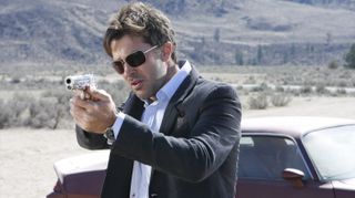 a still from Stargate: Atlantis showing a character in a suit wielding a pistol