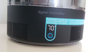 Image is a closeup of the base of the Dyson AM10 Humidifier, showing the power button and humidity target.
