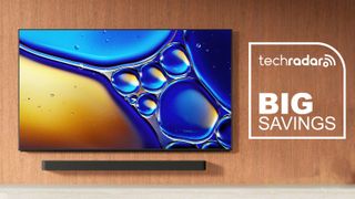 Sony Bravia 8 II QD-OLED TV mounted on a wall with a soundbar underneath. The TechRadar logo and "Big Savings" in white text is on the right.