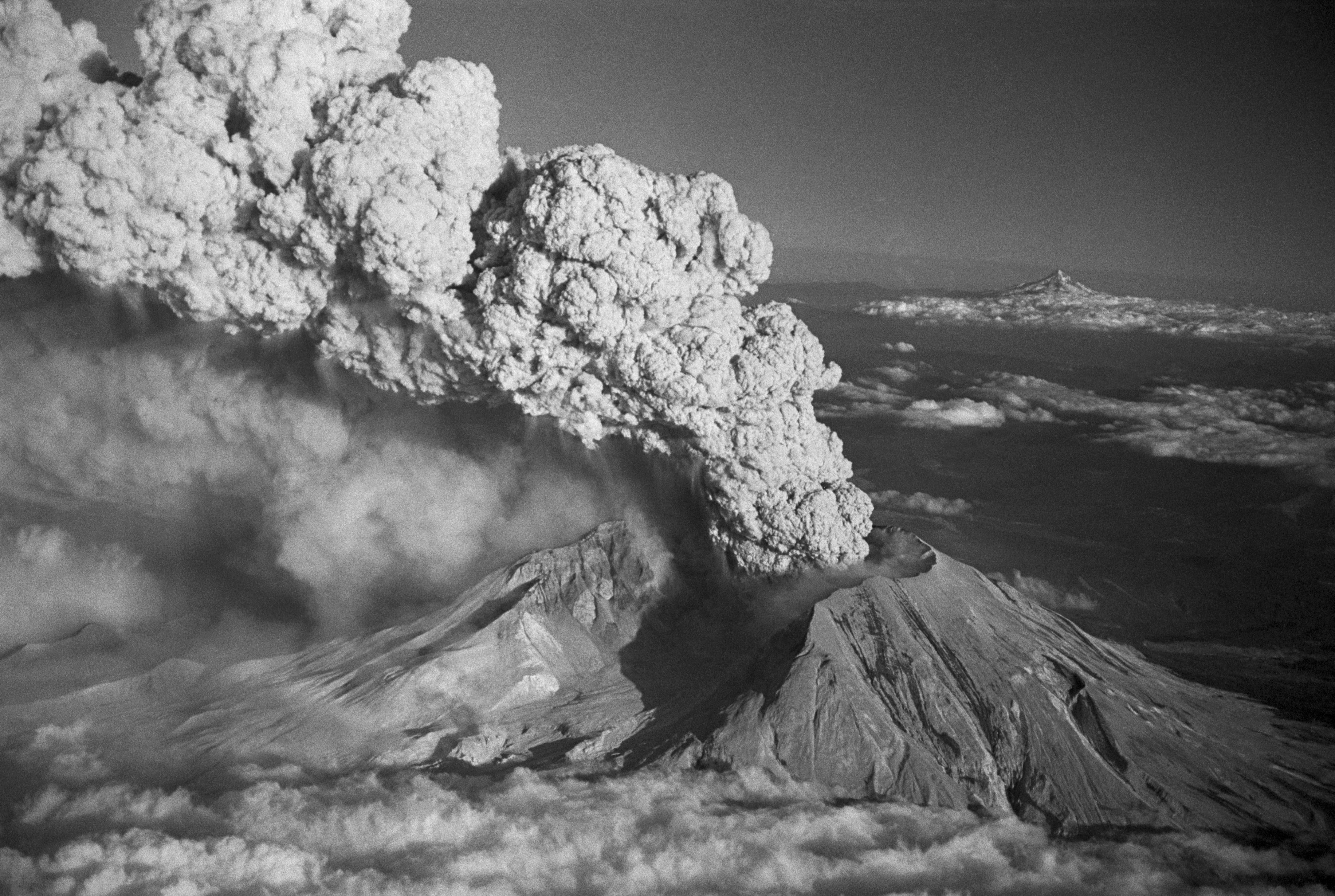 A volcano erupts in black and white.