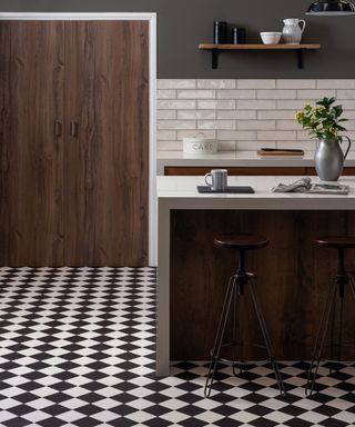 a classic black and white chequered floor in a wood kitchen with white subway tiles, dark wood cabinets, a kitchen island, bar stools and open shelving