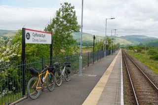 Two gravel bikes leaning against a set of rails at the Dovey Junction train station which is at the end of the Trans Cambrian Way