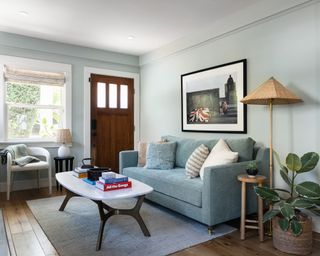 living room with pale blue walls, blue sofa, wooden floors and subtle red accents