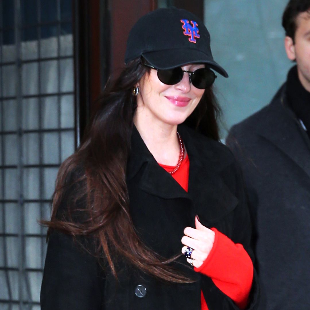 Dakota Johnson was spotted in New York City wearing a black pea coat, a red sweater, a suede jacket, leather boots, and a leopard-print Prada bag