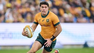 Ben Donaldson of the Wallabies runs with the ball in a yellow shirt and green shorts ahead of the Australia vs South Africa live stream at the 2024 Rugby Championship.