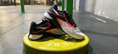 Pair of Reebok Nano X4 shoes on yellow weight plate