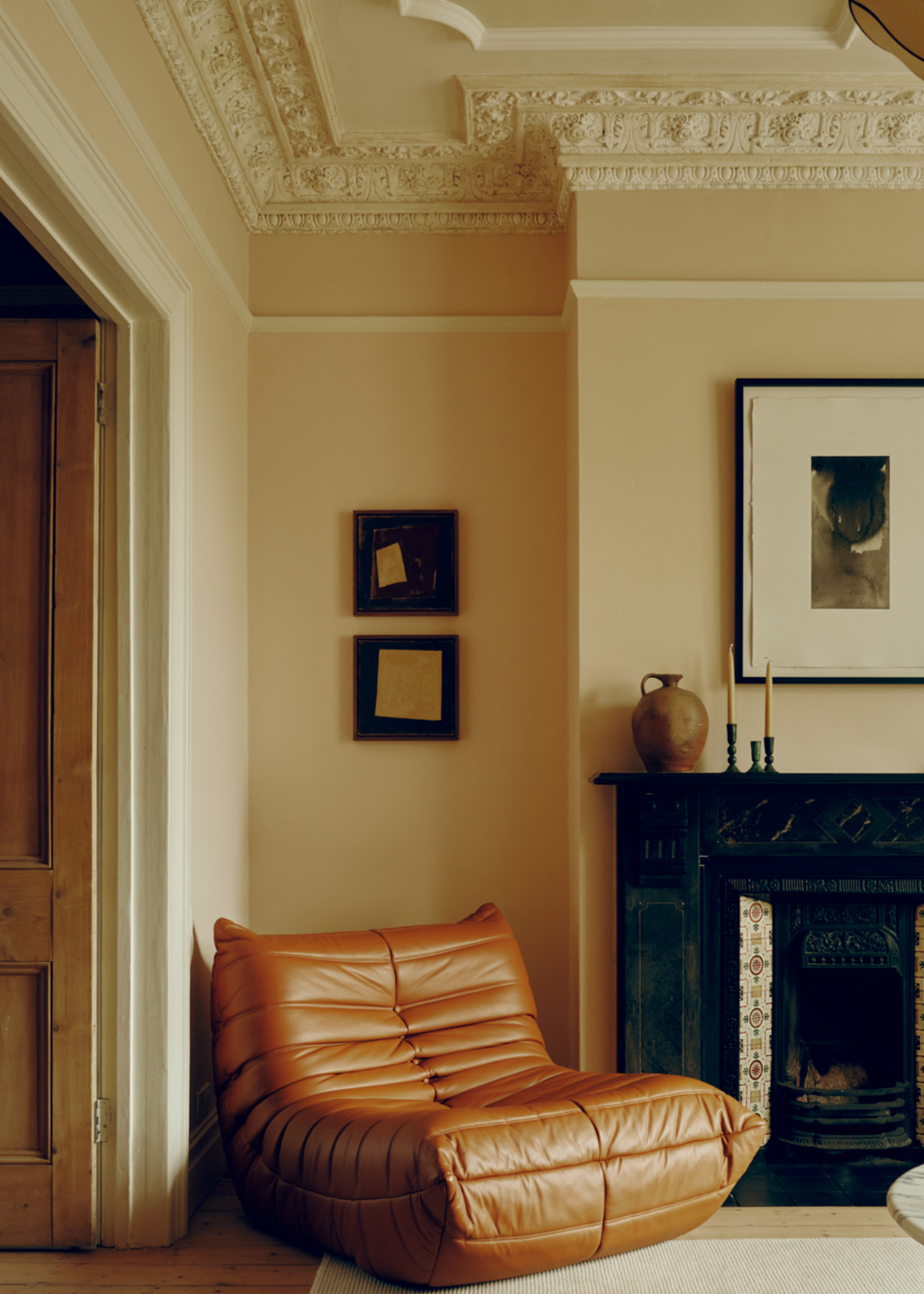 Renovated period living room with original fireplace and ceiling detail featuring a statement leather chair