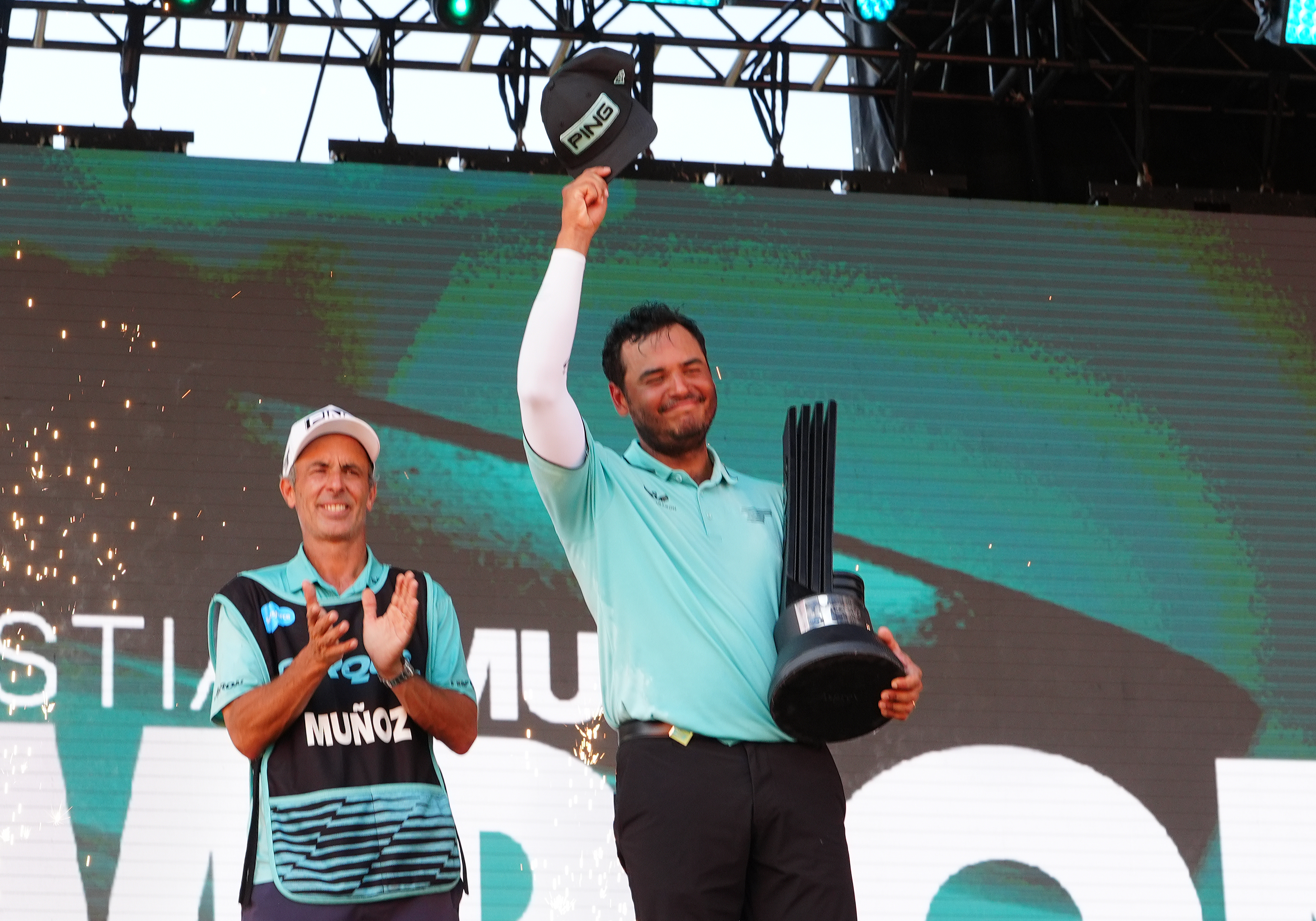 Sebastian Munoz holds a LIV Golf trophy on the podium