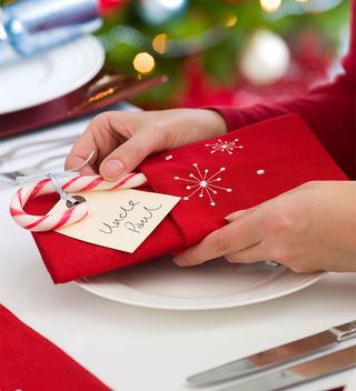 Christmas place setting with red napkin and candy cane