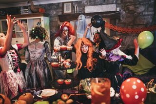 A group of people in costumes dancing in a house that has been decorated for Hallloween.