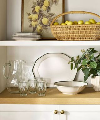 Ceramic plates, glasses and rattan basket with lemons on dresser