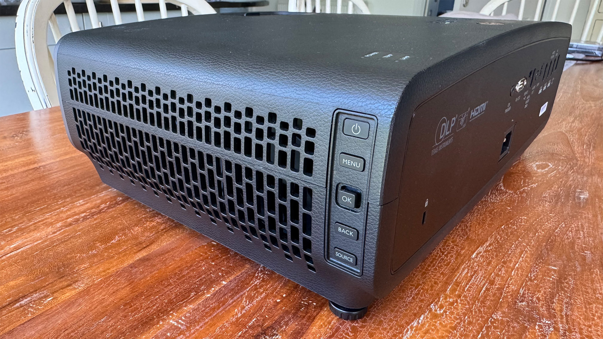The BenQ W2720i projector, pictured on a wooden table in a living room