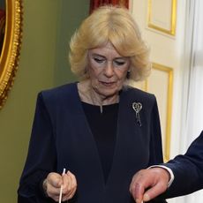 Queen Camilla wearing a blue jacket and a diamond heart brooch