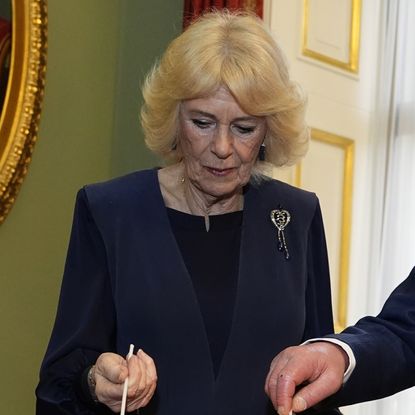 Queen Camilla wearing a blue jacket and a diamond heart brooch