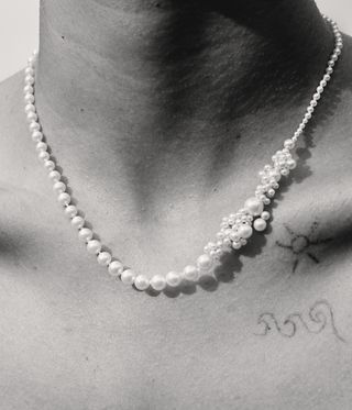 black and white image of woman wearing pearl necklace