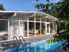 Fire Island pines tour includes this white house, timber structure and pool and warm interiors
