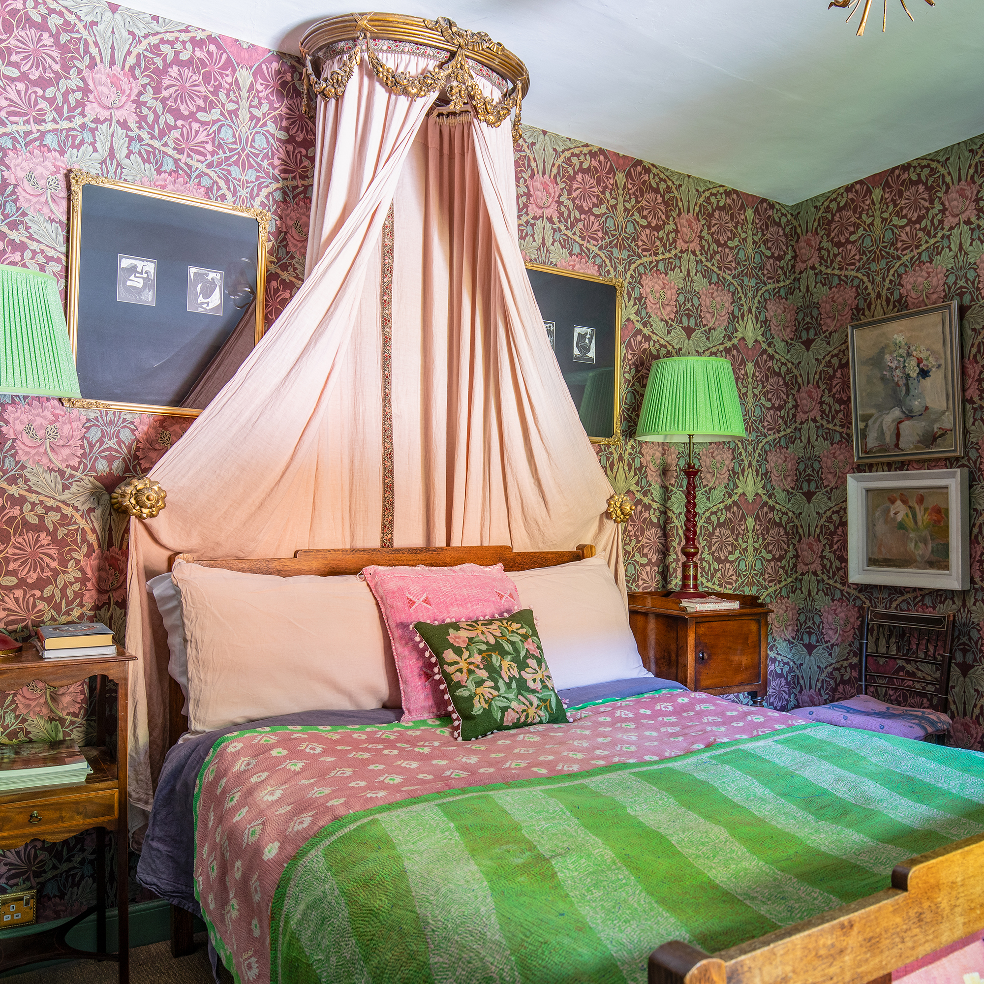 Bedroom wallpapered with William Morris print, with a vintage bed canopy and patterned bed covers