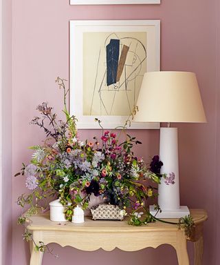 Pink entryway with wood console and floral arrangement