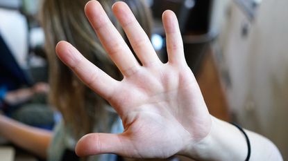 A woman holds up her hand in a stop gesture.