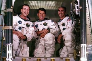 Apollo 7 crewmates Donn Eisele (at left), Wally Schirra (center) and Walt Cunningham, looking into the spacecraft's hatch.