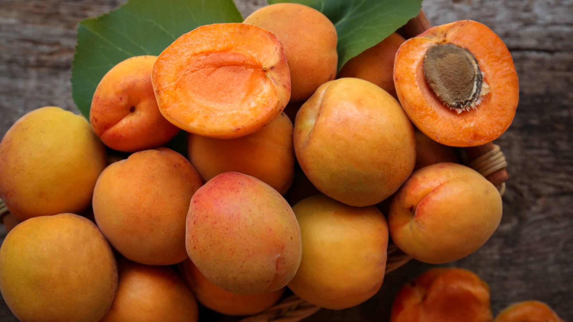 A pile of apricots, one sliced in half exposing the pit