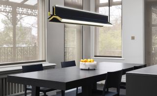 A dining area with a black table, chairs and a large angular black pendant light.