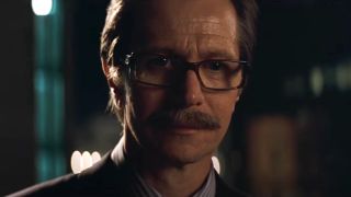 Gary Oldman's Jim Gordon looking down at Batman as he jumps off rooftop