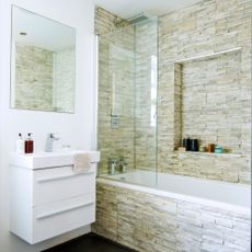 bathroom with textured wall and washbasin and bathtub