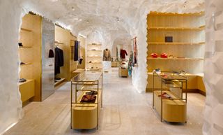Interior of fashion store with white textured walls and ceiling and wooden shelves and display cases