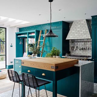 blue cabinets with black stools, wooden island worktop and black pendant light