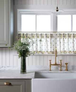 english style kitchen with green cabinets marble countertop and a cafe curtain