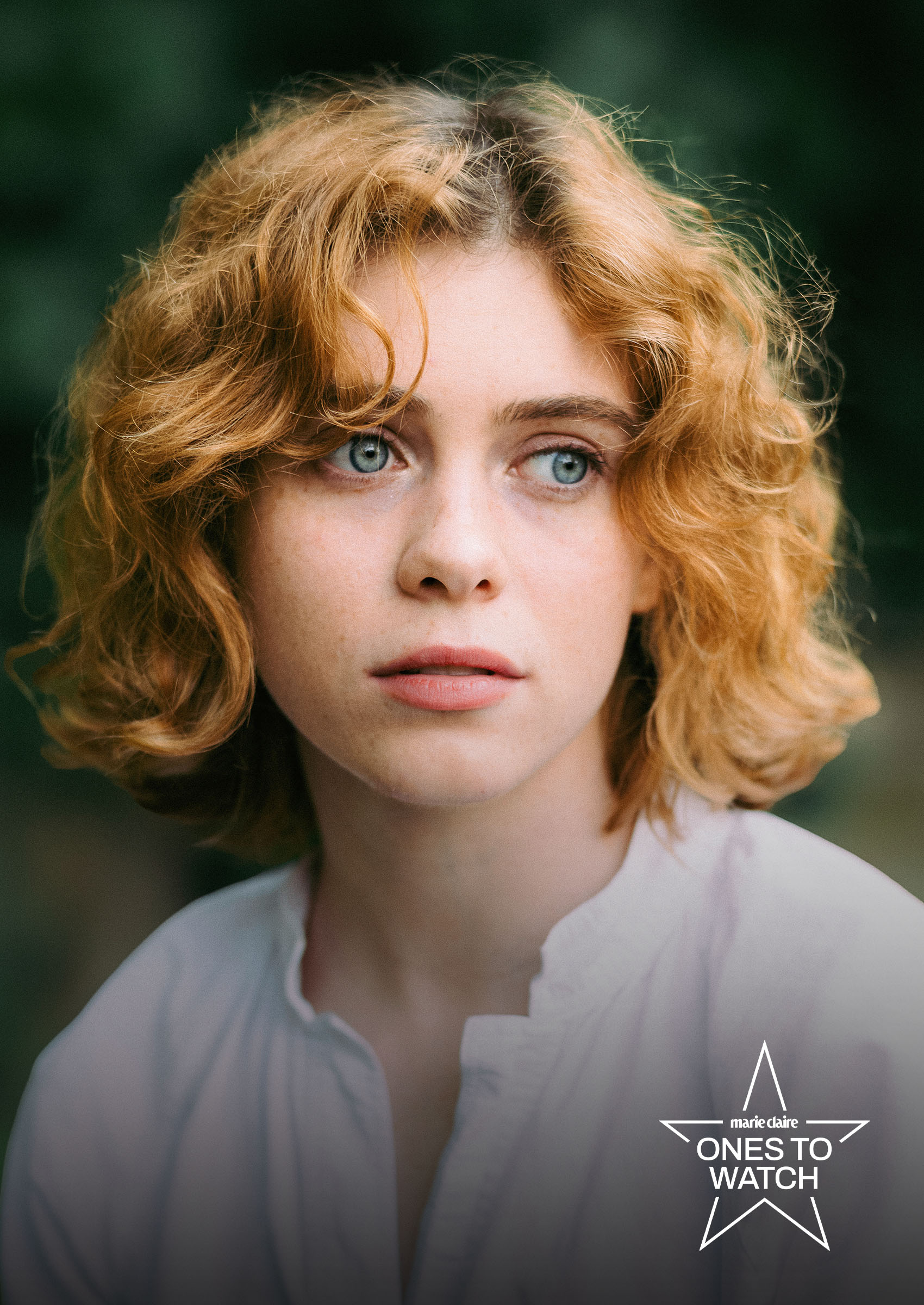 actress sophia lillis poses with a curly bob wearing a white top outside