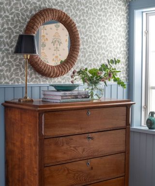 wallpapered vintage bedroom with rattan mirror