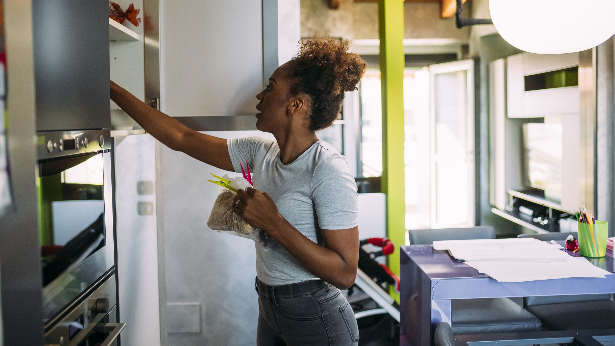Woman reaches into a kitchen cabinet